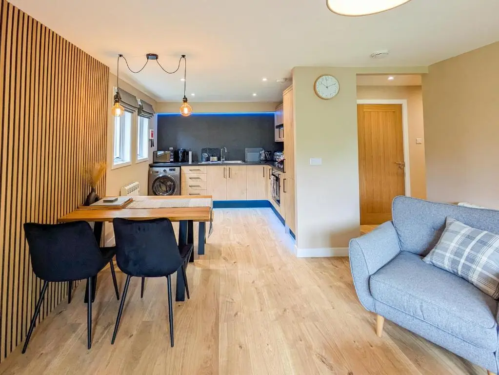 a kitchen and living room with a table and a couch at Highland Cow Apartment in Inverness