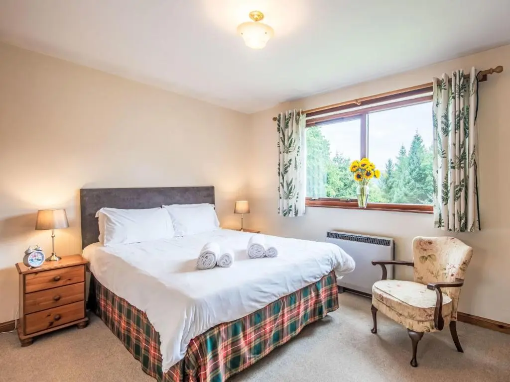 a bedroom with a bed and a chair and a window at Holiday Home Farmburn by Interhome in Invermoriston
