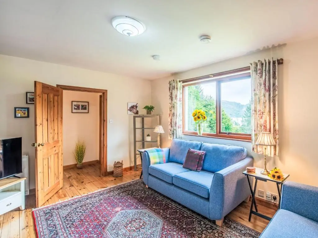 a living room with a blue couch and a window at Holiday Home Farmburn Bothy by Interhome in Invermoriston