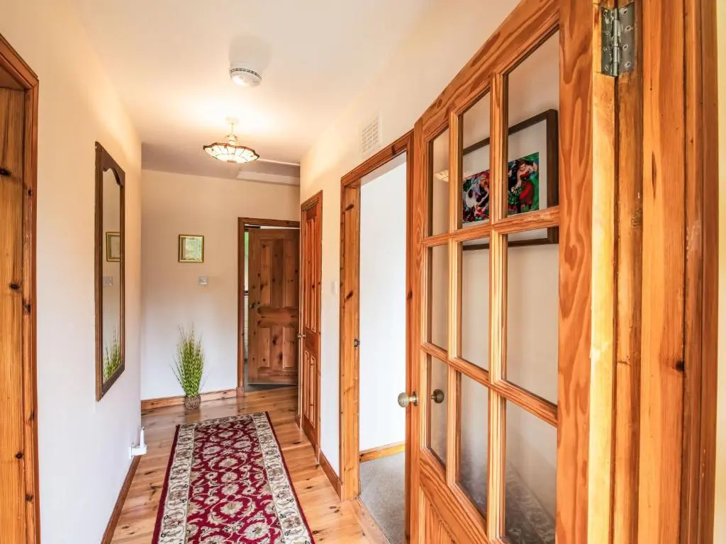 a hallway with wooden doors and a rug at Holiday Home Farmburn Bothy by Interhome in Invermoriston
