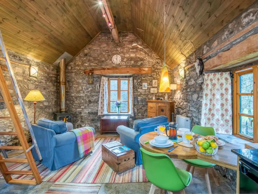 a living room with a table and blue chairs at Holiday Home Farmburn Bothy by Interhome in Invermoriston