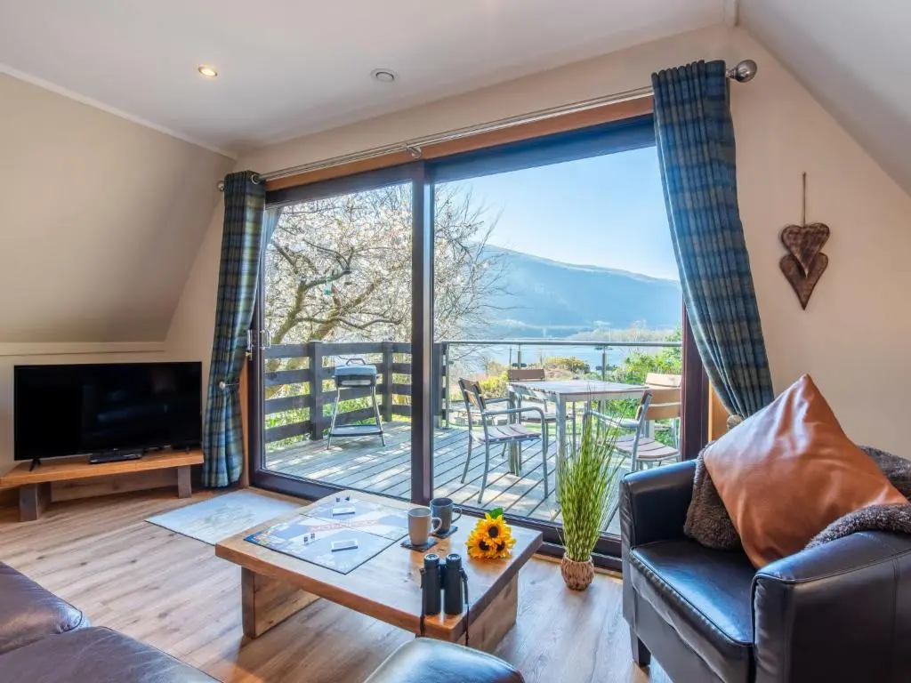 a living room with a couch and a large window at Chalet Sandpiper Lodge by Interhome in Spean Bridge