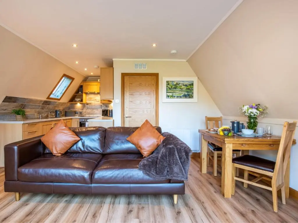 a living room with a leather couch and a table at Chalet Sandpiper Lodge by Interhome in Spean Bridge