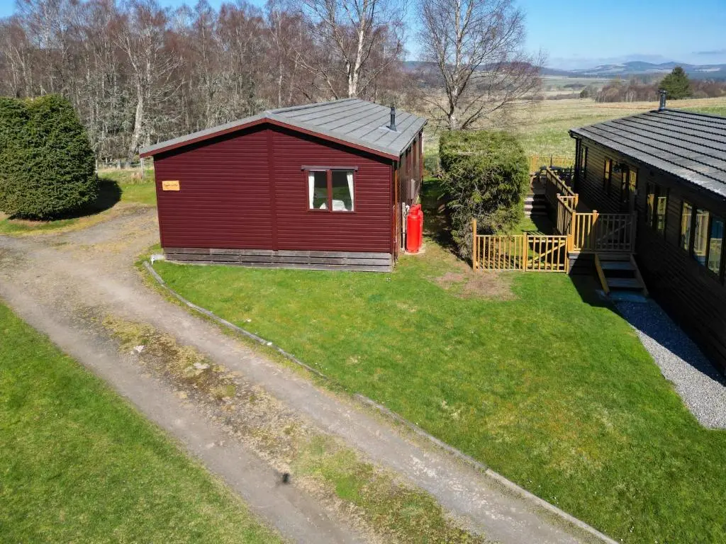 a small red building with a dog in a window at Chalet Lodge 5 by Interhome in Boat of Garten