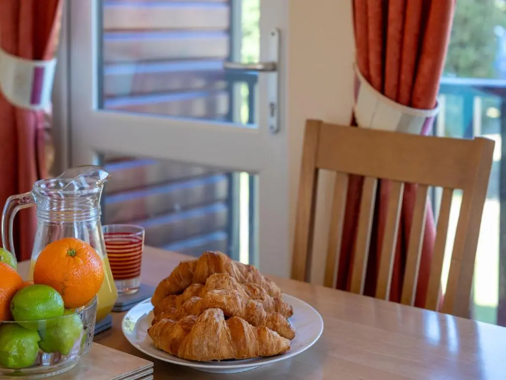 a table with a plate of bread and fruit on it at Chalet Lodge 5 by Interhome in Boat of Garten