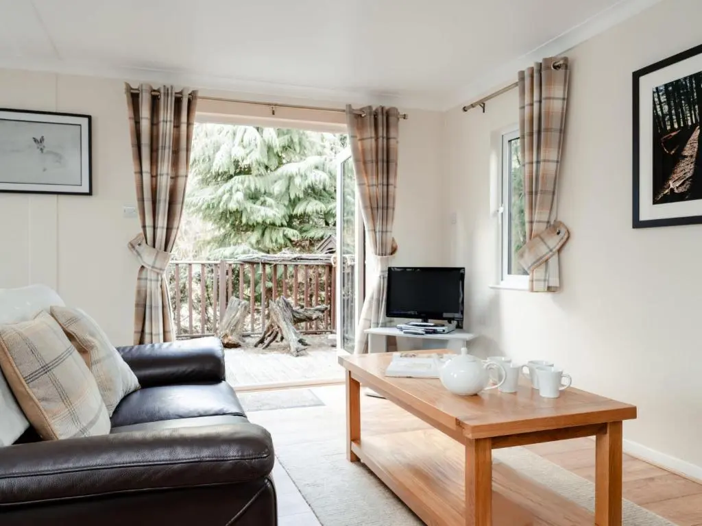 a living room with a couch and a table at Chalet Lodge 7 by Interhome in Boat of Garten