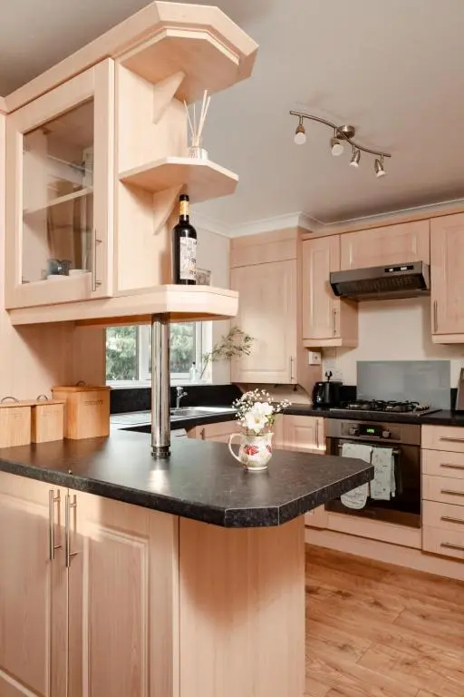 a kitchen with a black counter top and wooden cabinets at Chalet Lodge 7 by Interhome in Boat of Garten