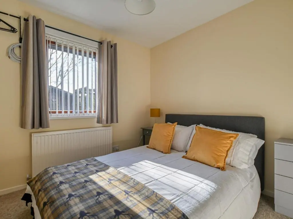 a bedroom with a bed with orange pillows and a window at Holiday Home Appletree by Interhome in Muir of Ord