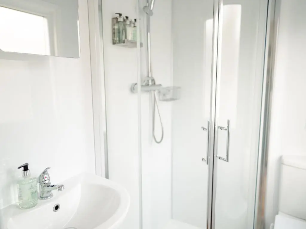 a white bathroom with a shower and a sink at Chalet Lodge 8 by Interhome in Boat of Garten