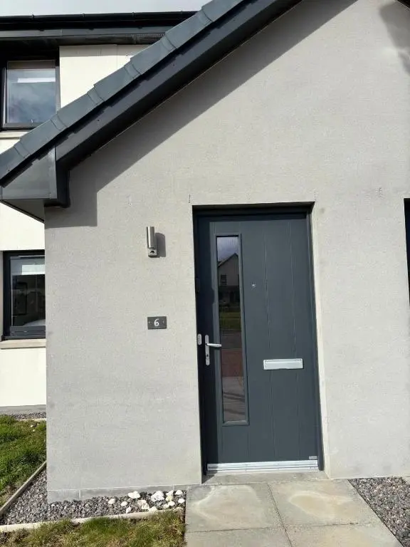 a black door on a white house at Gorgeous Dornoch apartment in Dornoch