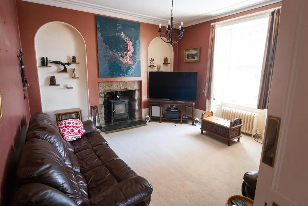 a living room with a leather couch and a television at The Old Manse Oyne in Oyne