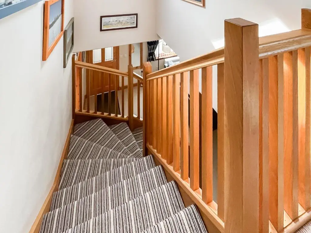 a winding staircase with wooden railings in a house at Rowlands in Aviemore