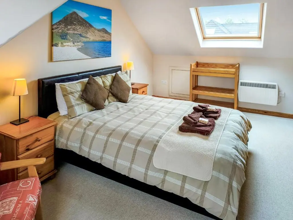 a bedroom with a large bed and a window at Rowlands in Aviemore