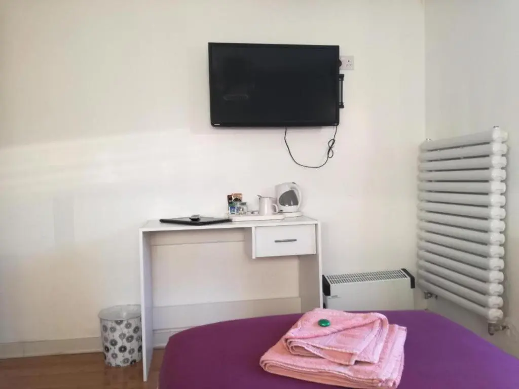 a room with a table and a tv on the wall at Ardenlea House Hotel B&b in Dyce