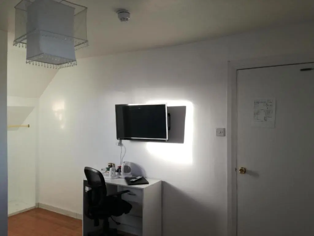 a room with a desk with a television on a wall at Ardenlea House Hotel B&b in Dyce