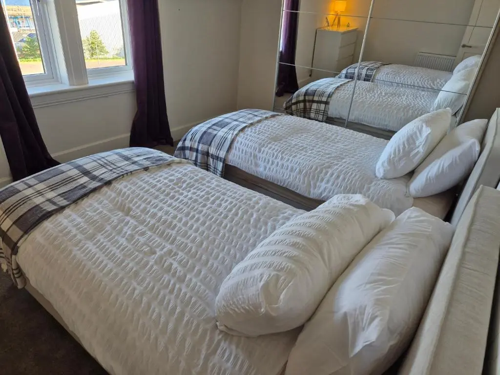 two twin beds in a room with two windows at Dalwhinnie in Buckie