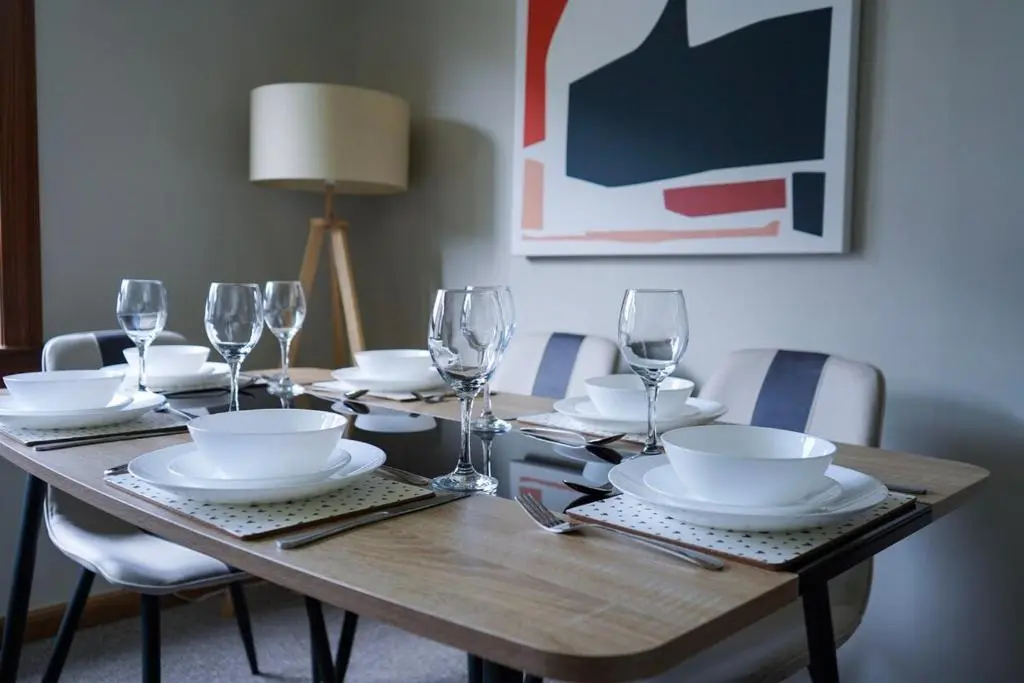 a wooden table with plates and wine glasses on it at Rosehearty house - 3 bedroom in Rosehearty