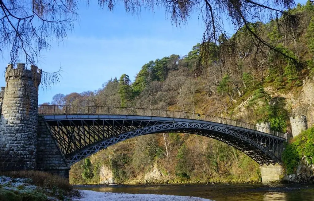 a bridge over a river in front of a mountain at West Lodge, High Street in Aberlour