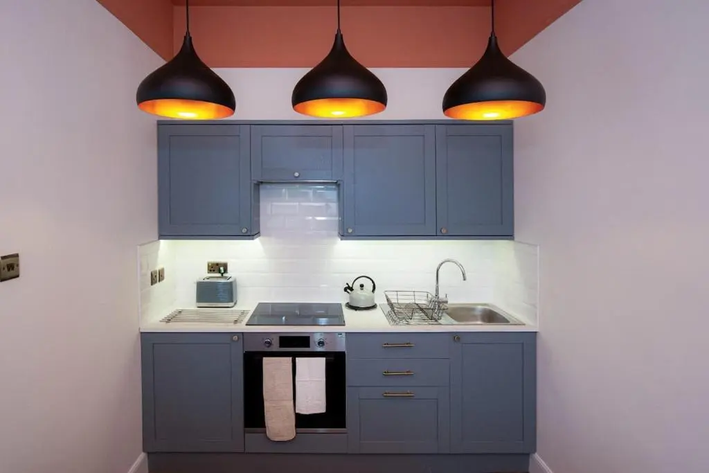 a kitchen with blue cabinets and a sink and lights at West Lodge, High Street in Aberlour
