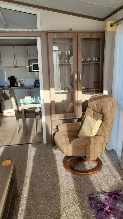 a living room with a chair and a kitchen at Northern Light Villa, forest, beach and bubbles in Burghead