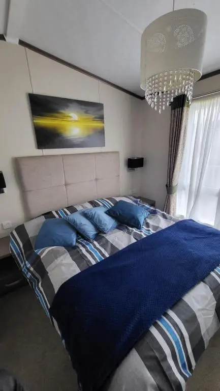 a bedroom with a large bed with blue pillows at Northern Light Villa, forest, beach and bubbles in Burghead
