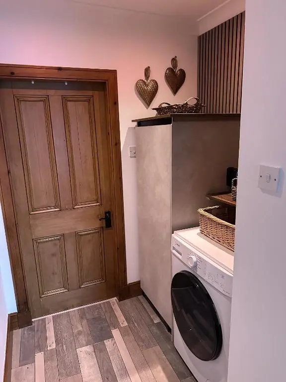 a laundry room with a door and a washing machine at Sealladh Sona in Inverness