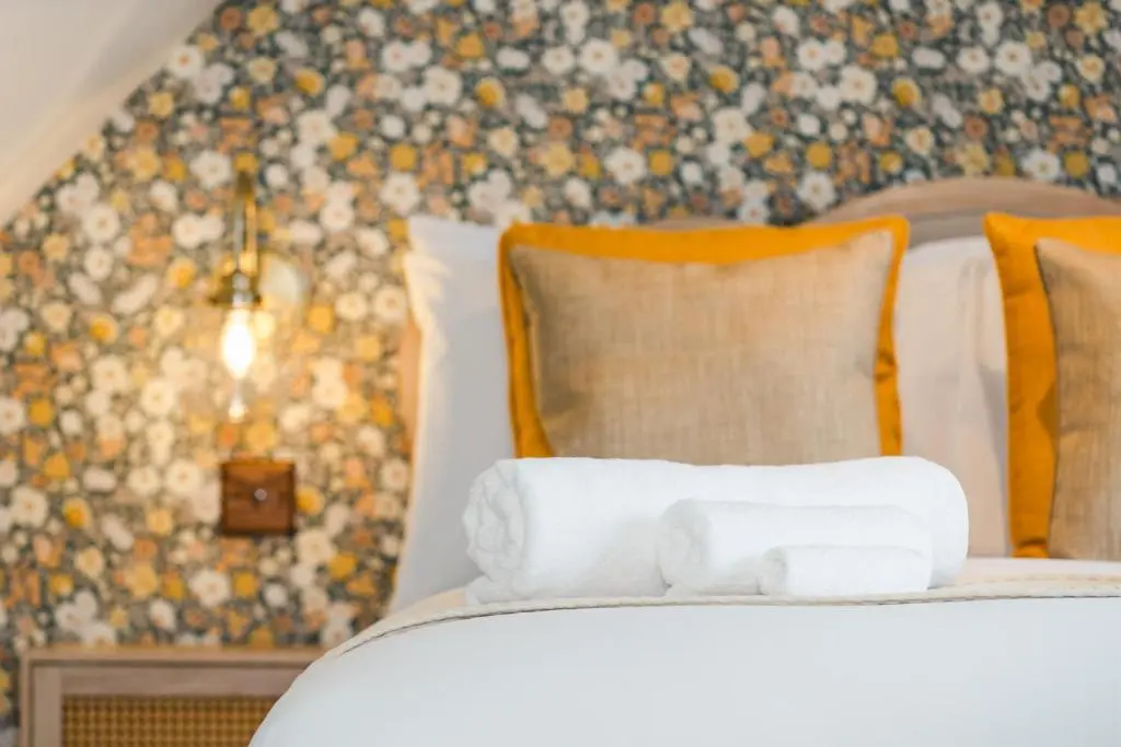a bedroom with a bed with pillows and a floral wall at Keel Cottage & Dog Friendly in Nairn