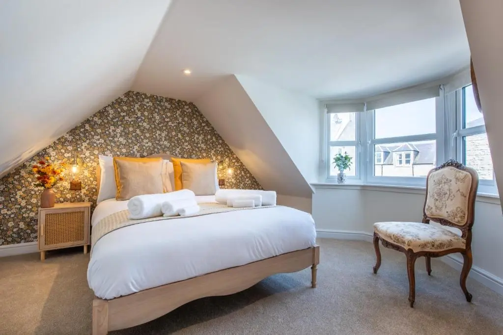 a bedroom with a large bed and a chair at Keel Cottage & Dog Friendly in Nairn