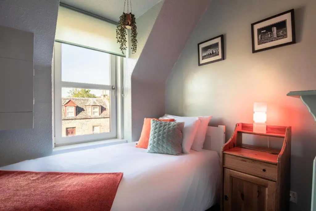 a bedroom with a white bed and a window at Laughlin House in Inverness