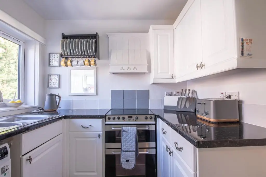 a kitchen with white cabinets and black counter tops at Laughlin House in Inverness