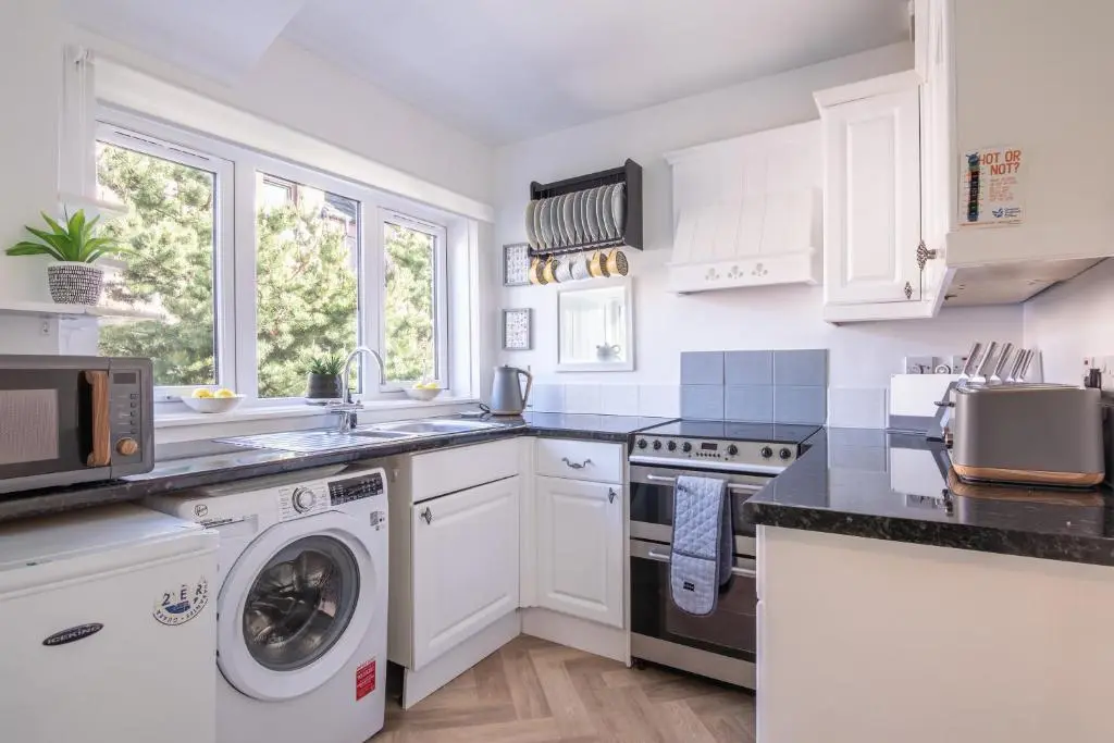 a kitchen with white cabinets and a washer and dryer at Laughlin House in Inverness