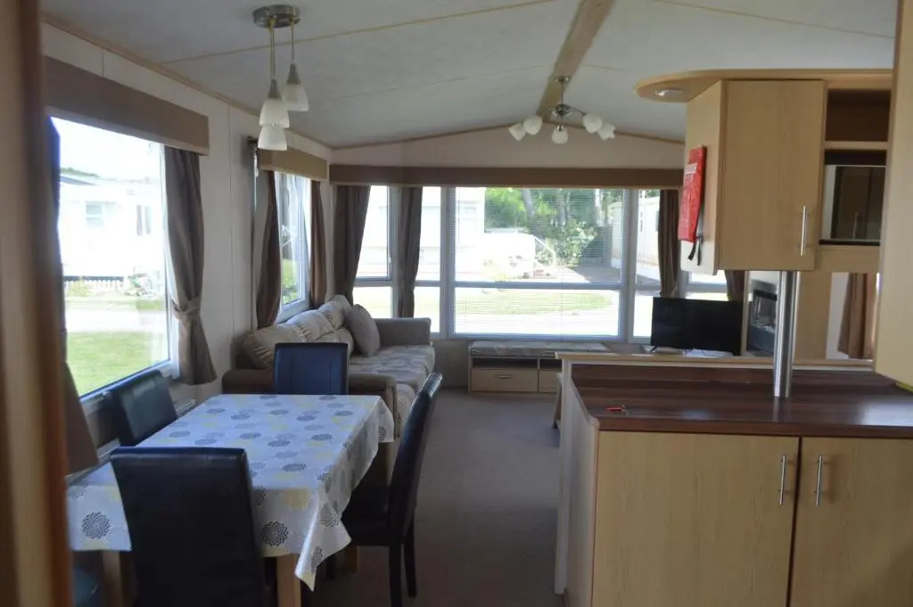 a kitchen and a living room with a table and a couch at C5, The Old Mill Caravan Park, Brodie in Dyke