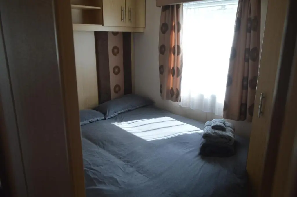 a small room with a bed and a window at C5, The Old Mill Caravan Park, Brodie in Dyke