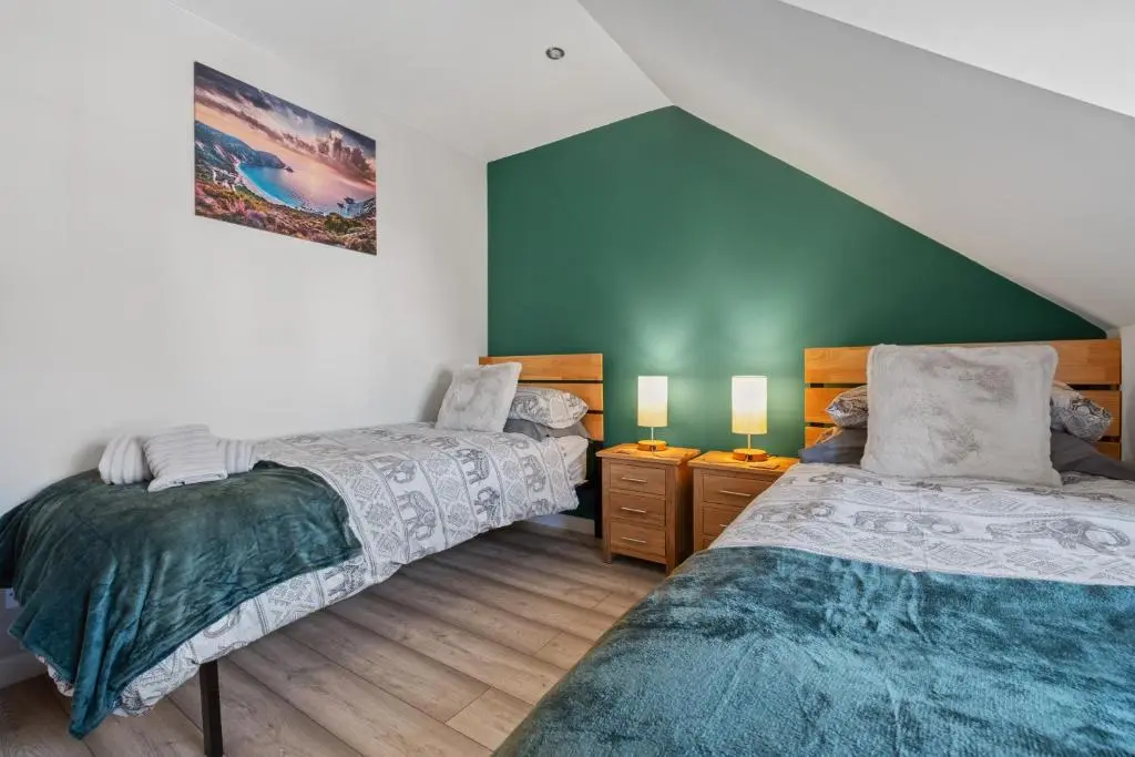 two beds in a room with green walls at Caledonian Buildings 20b stylish city centre apartment in Inverness