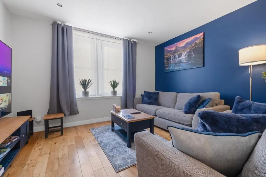 a living room with blue walls and a couch at Caledonian Buildings 20b stylish city centre apartment in Inverness