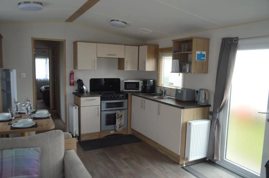 a kitchen with white cabinets and a stove top oven at B5 at The Old Mill Holiday Park in Dyke