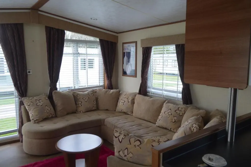 a living room with a large couch and windows at B8 at The Old Mill Holiday Park in Dyke