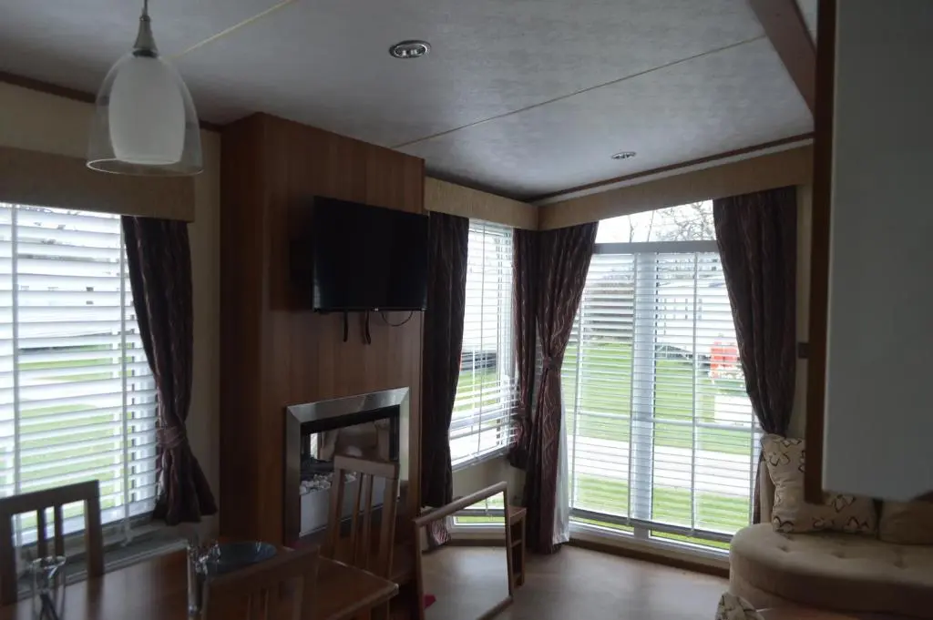 a living room with large windows and a tv at B8 at The Old Mill Holiday Park in Dyke