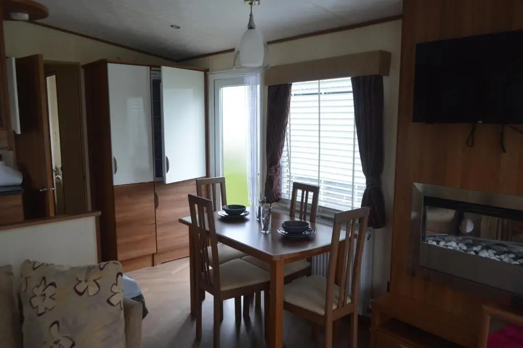 a dining room with a table and chairs and a television at B8 at The Old Mill Holiday Park in Dyke