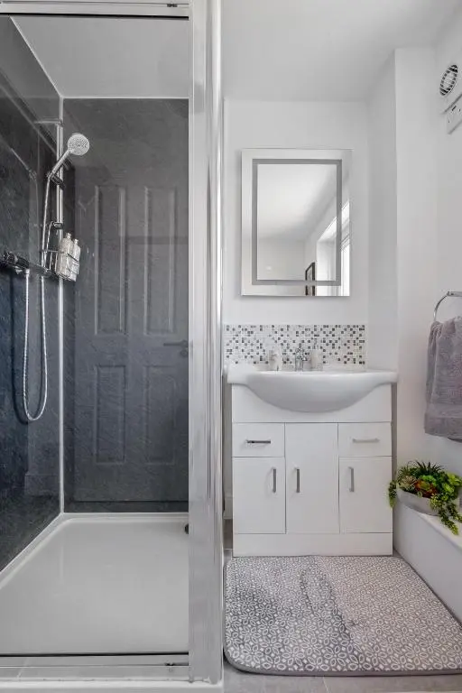 a white bathroom with a shower and a sink at Inverness Riverside Apartment with Parking in Inverness
