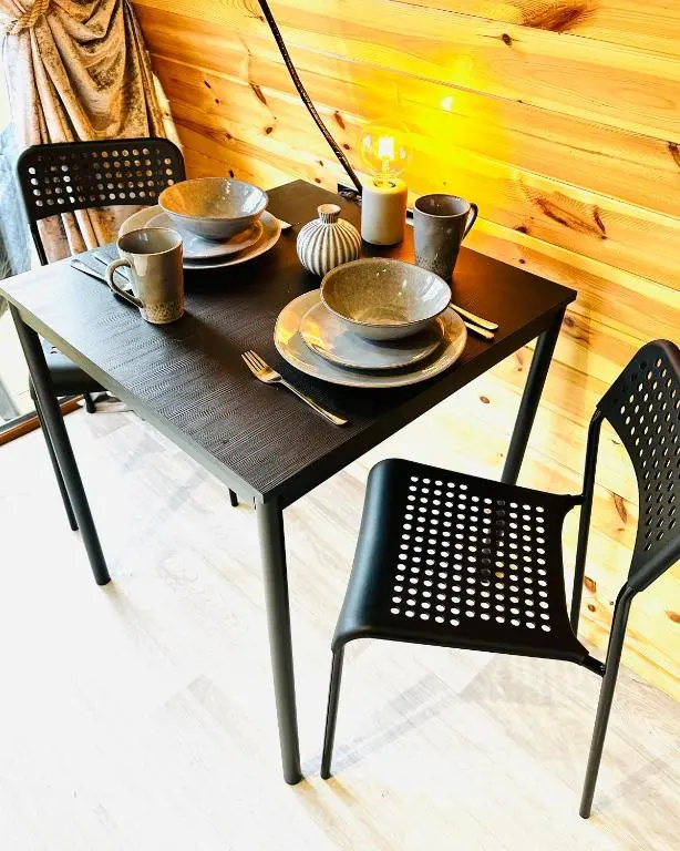 a wooden table with plates and cups and chairs at Brora Escapes in Brora