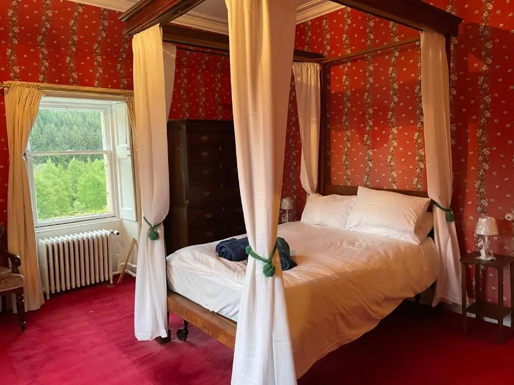a bedroom with a canopy bed and a window at Glentromie Estate in Ruthven