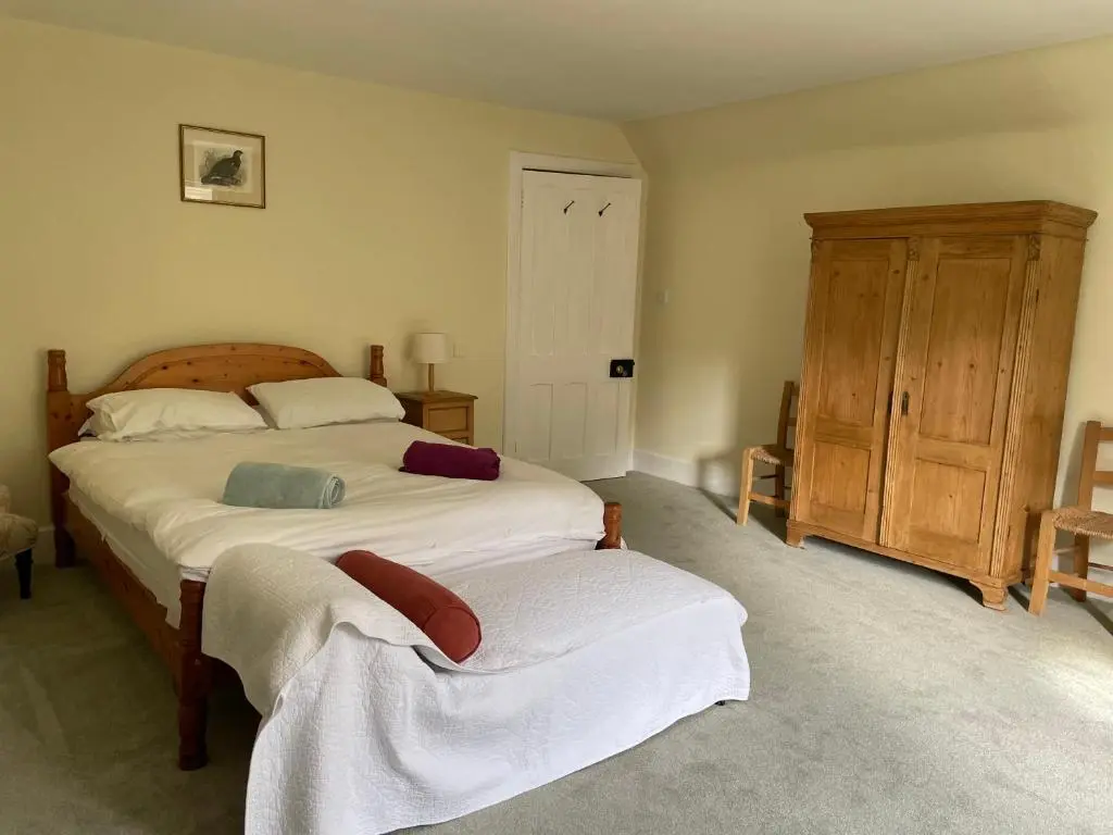 a bedroom with a large bed and a wooden cabinet at Glentromie Estate in Ruthven