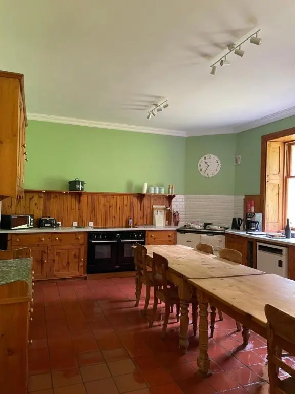a kitchen with a table and a clock on the wall at Glentromie Estate in Ruthven