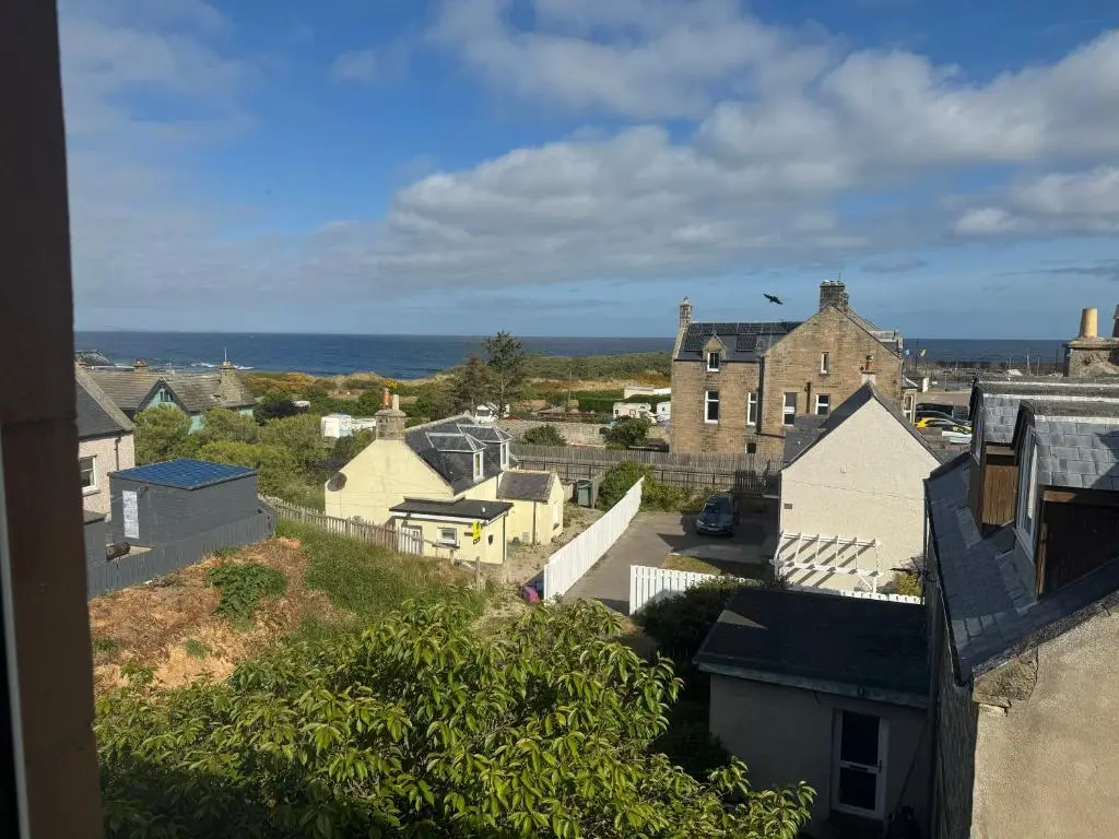 a view of a town with houses and the ocean at Harbour View Hopeman in Hopeman