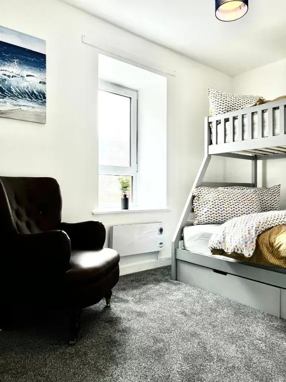 a bedroom with a bunk bed and a chair at Harbour View Hopeman in Hopeman