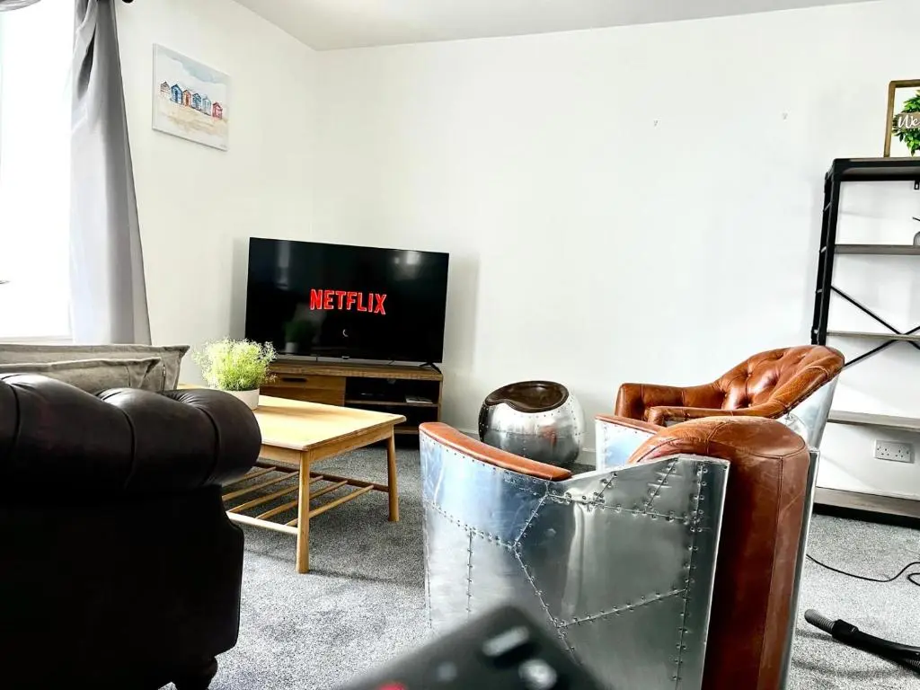 a living room with two leather chairs and a tv at Harbour View Hopeman in Hopeman