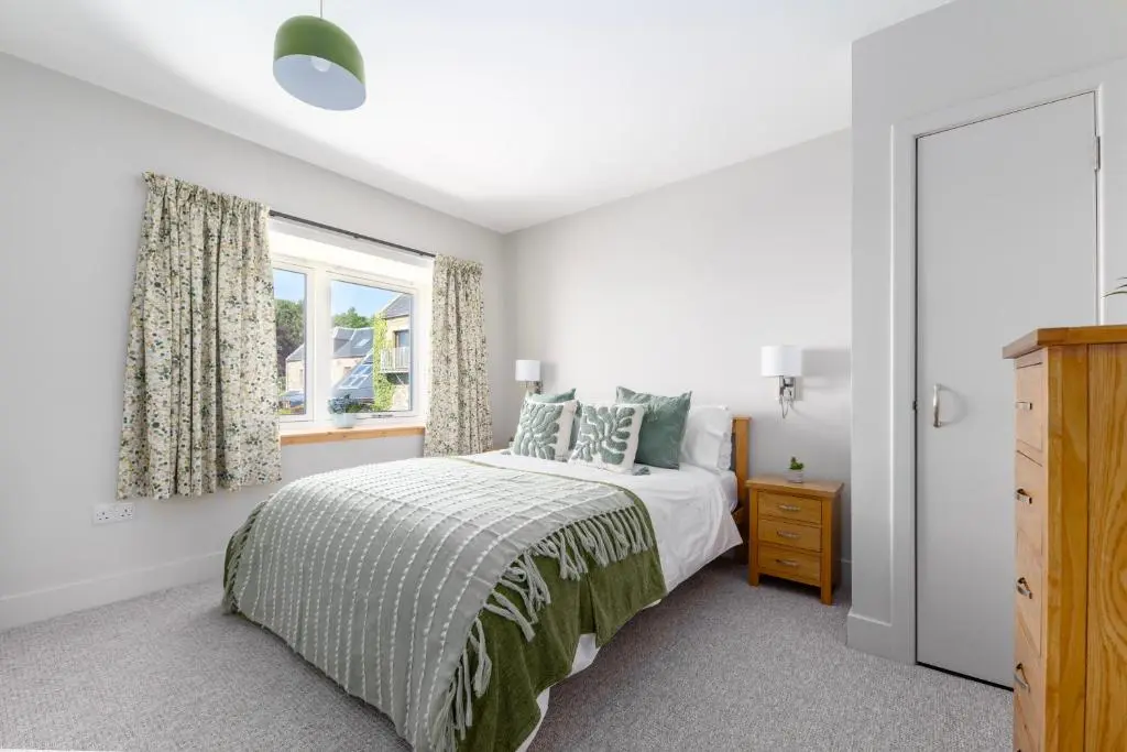 a white bedroom with a bed and a window at Firthview Fortrose in Fortrose