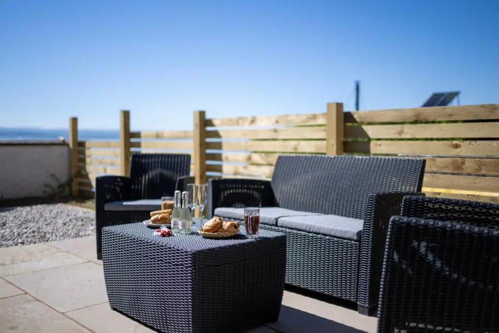 a patio with chairs and a table with food on it at Firthview Fortrose in Fortrose