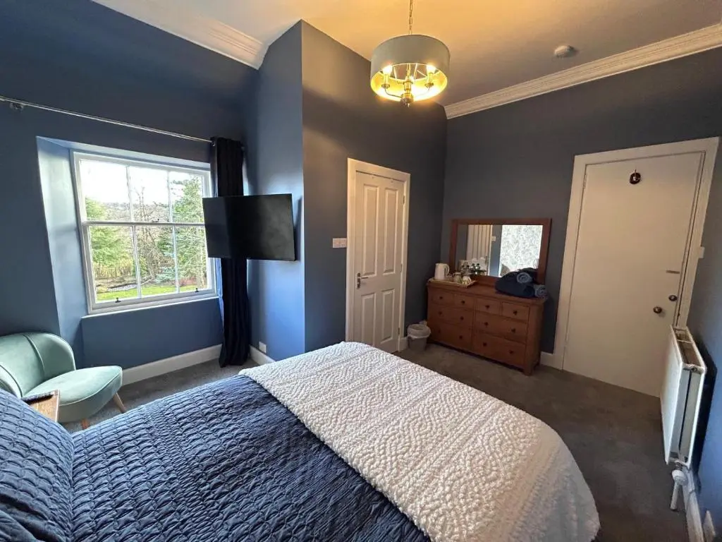 a bedroom with a bed and a television and a window at Gruinard Guest House in Beauly